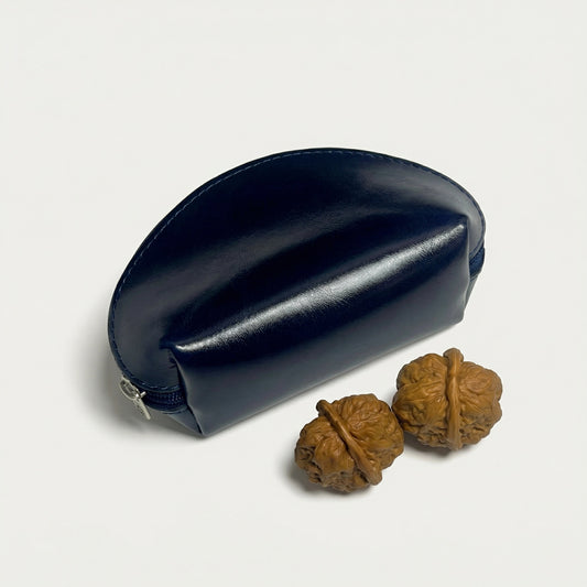 Navy blue leather case with two walnuts on a light gray background