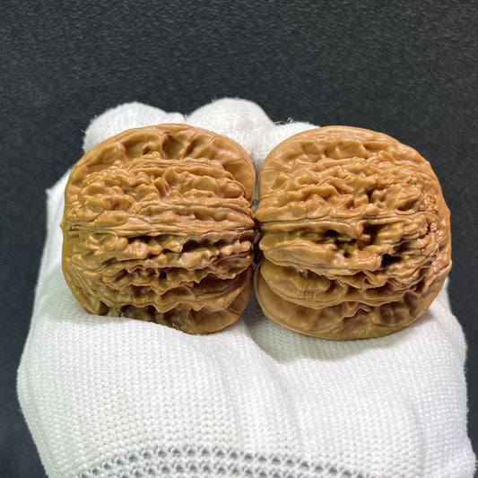Pair of walnut lion's head hand exercisers from ThePatinaProject, 43mm x 40mm, with detailed carved lion's head design.