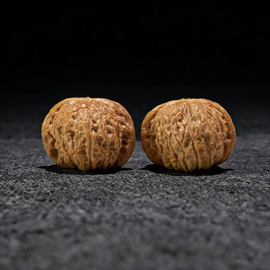 Pair of Blood Qilin walnut hand exercisers from ThePatinaProject, 37mm x 39mm, featuring intricate carved designs.