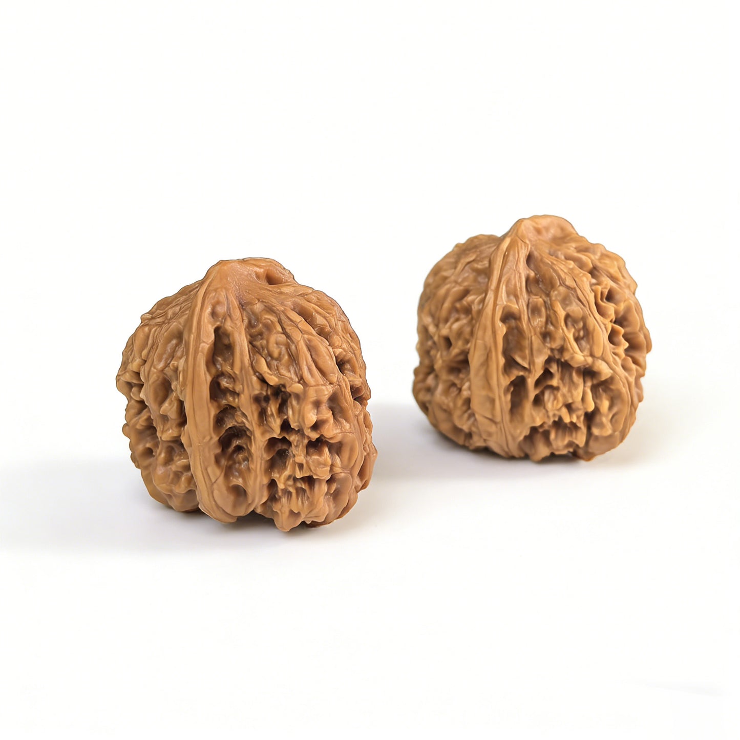 Walnut hand exercisers named Caterpillar by ThePatinaProject, 34mm size, showing the textured walnut surface and ergonomic shape.