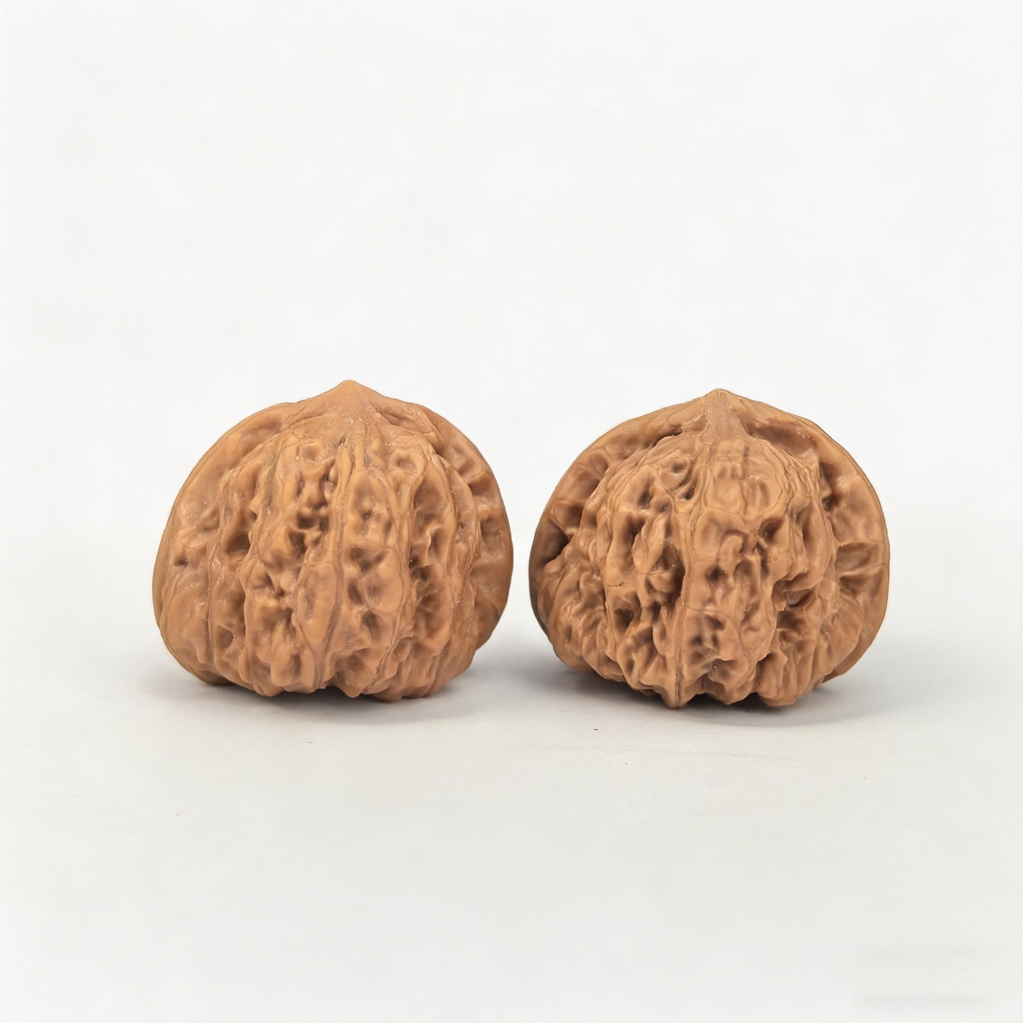 Walnut hand exercisers pair with yuanbao design, 32mm x 31mm, by ThePatinaProject, showing textured wood surface and unique shape.