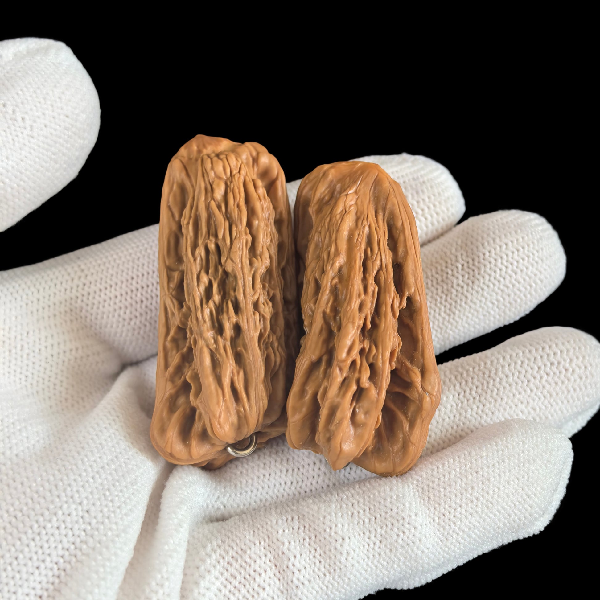 Walnut hand exerciser with double pendant set featuring gold bar and elongated symbol, designed for grip strengthening.