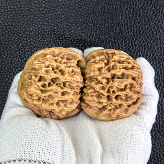 Pair of walnut hand exercisers from ThePatinaProject's Hundred Longevity series, measuring 47mm by 43mm, showing smooth polished surfaces.