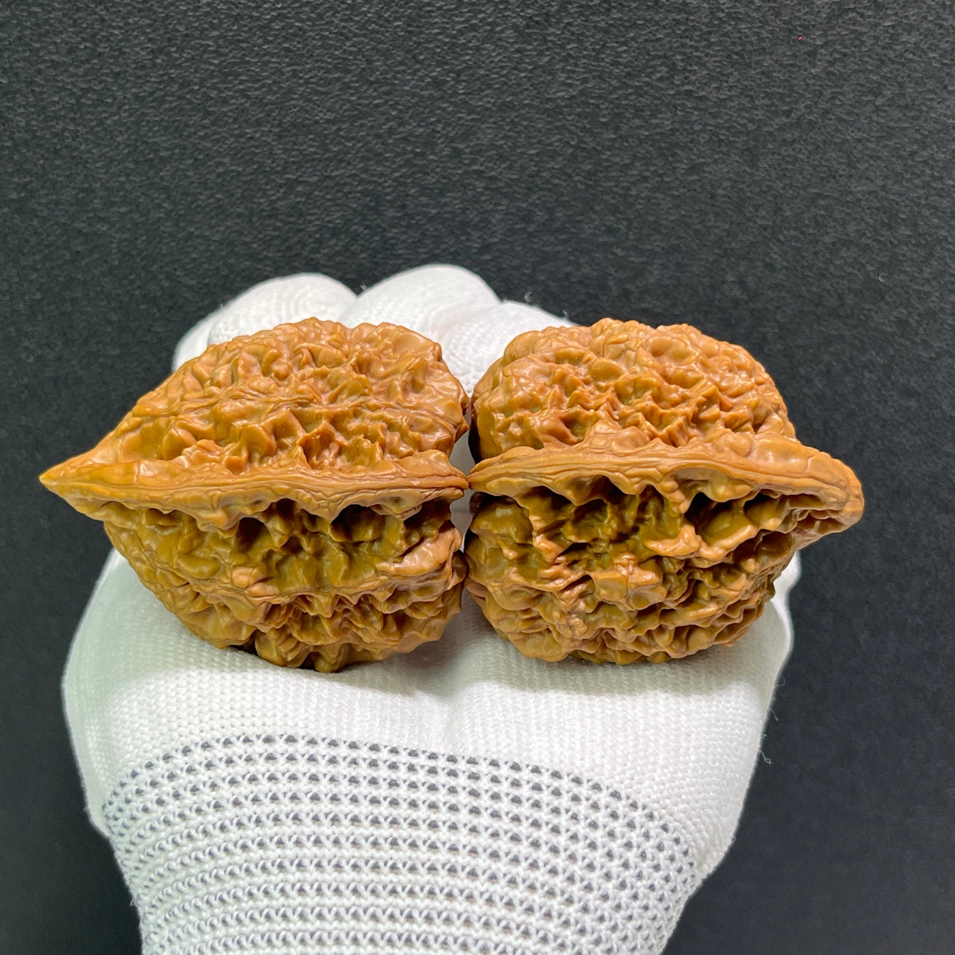 Walnut hand exercisers with large official's hat design, DGM-512 model by ThePatinaProject, showing textured walnut surface and detailed emblem.