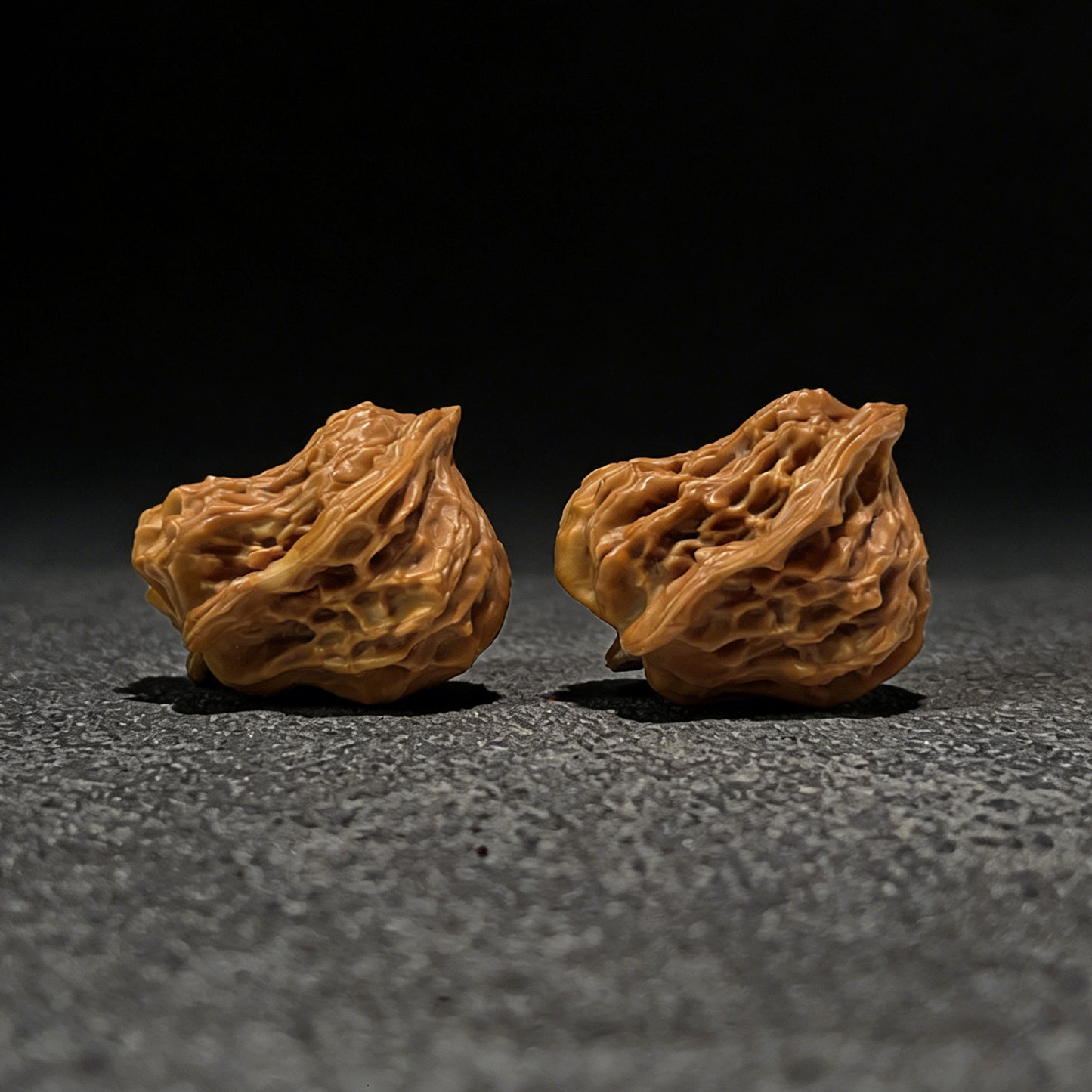 Walnut hand exerciser pair called The "Little Bird" by ThePatinaProject, 35mm by 28mm, showing textured walnut surface and ergonomic shape.