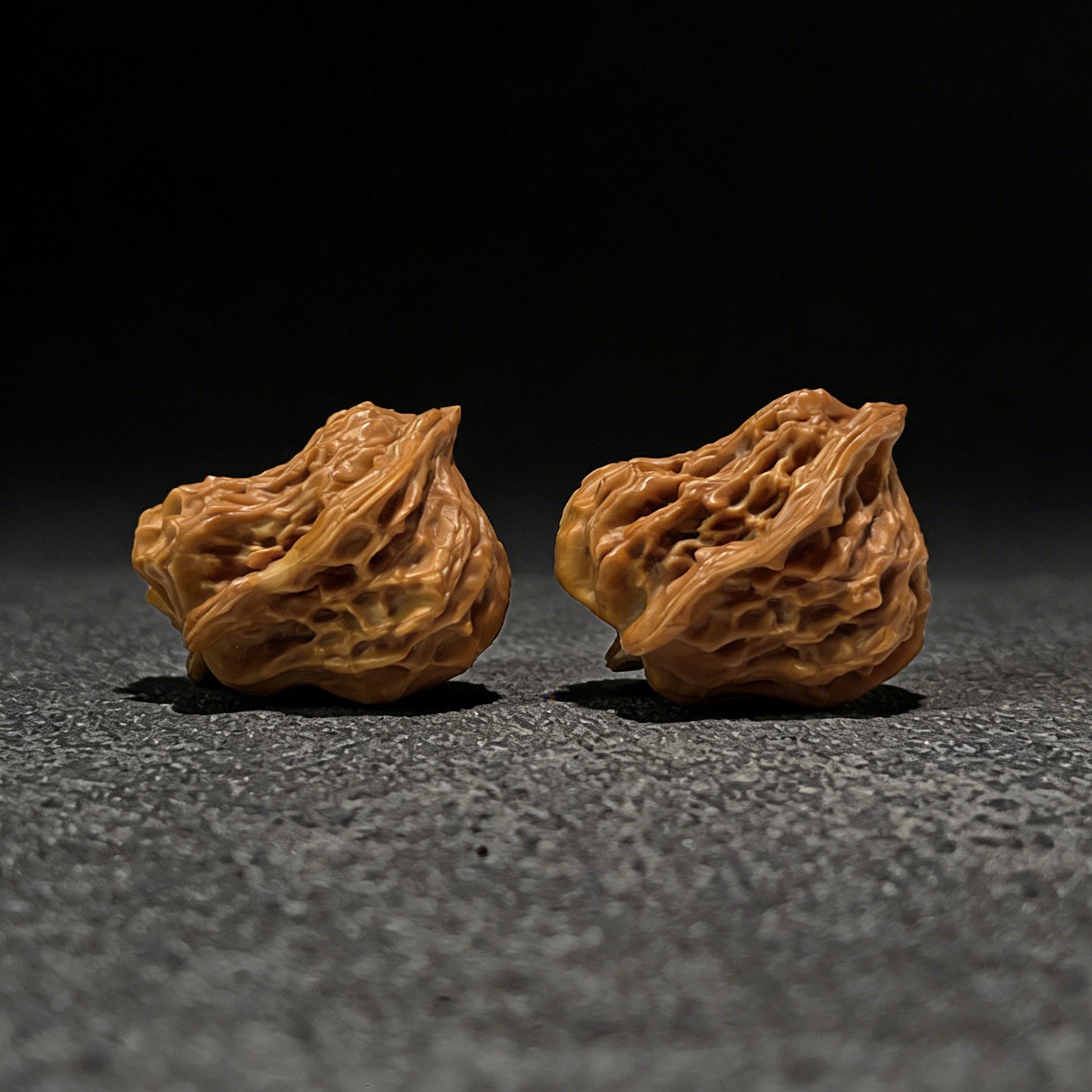 Walnut hand exerciser pair called The "Little Bird" by ThePatinaProject, 35mm by 28mm, showing textured walnut surface and ergonomic shape.
