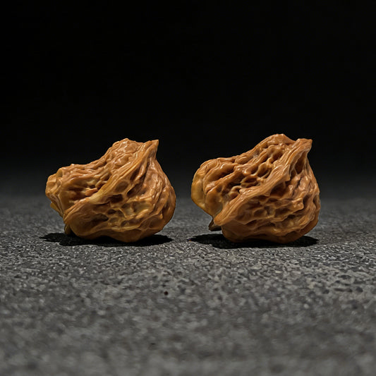 Walnut hand exerciser pair called The "Little Bird" by ThePatinaProject, 35mm by 28mm, showing textured walnut surface and ergonomic shape.