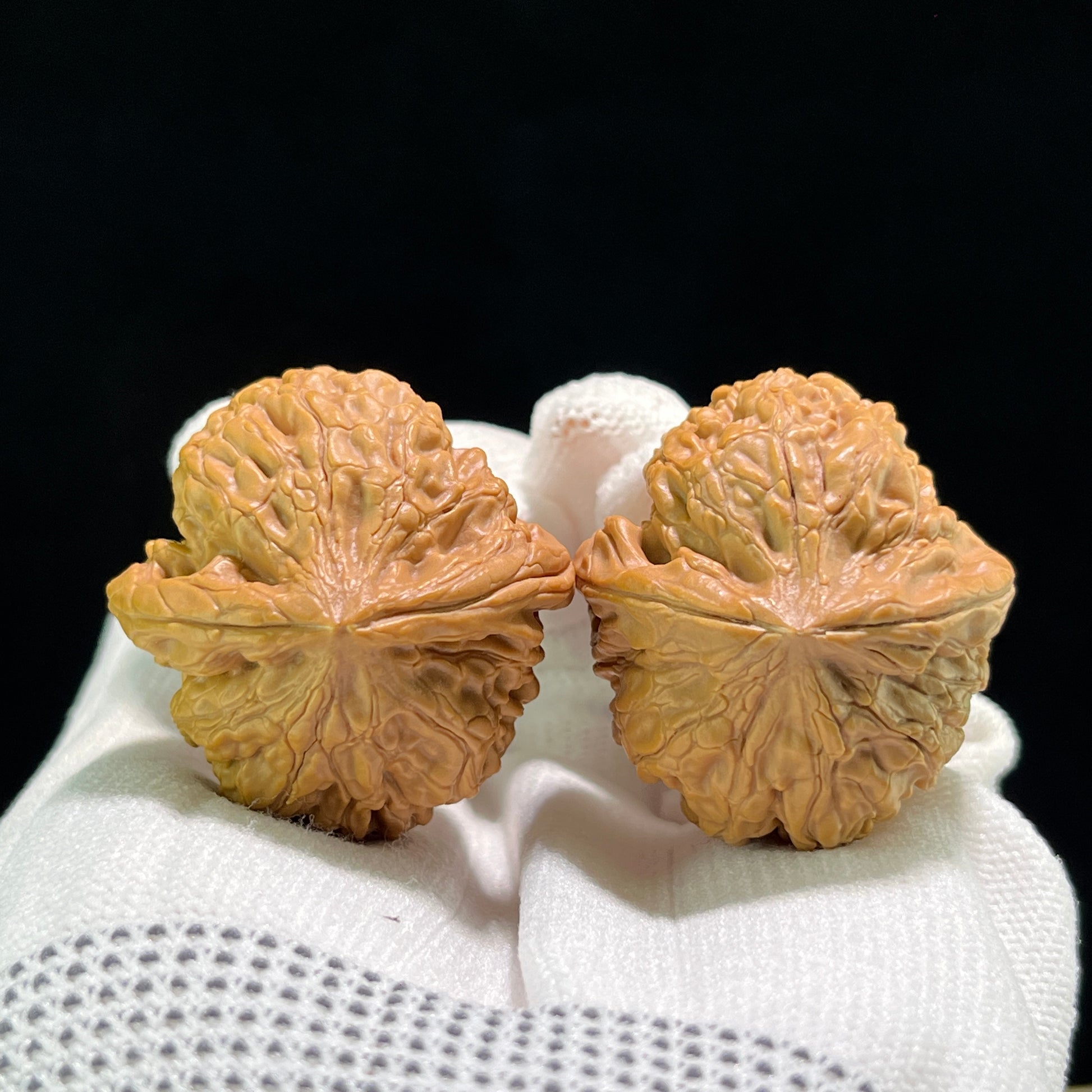 Walnut hand exerciser pair labeled Lotus (Lian Hua), 35mm x 38mm, LH-702, from ThePatinaProject, showing textured walnut surfaces.
