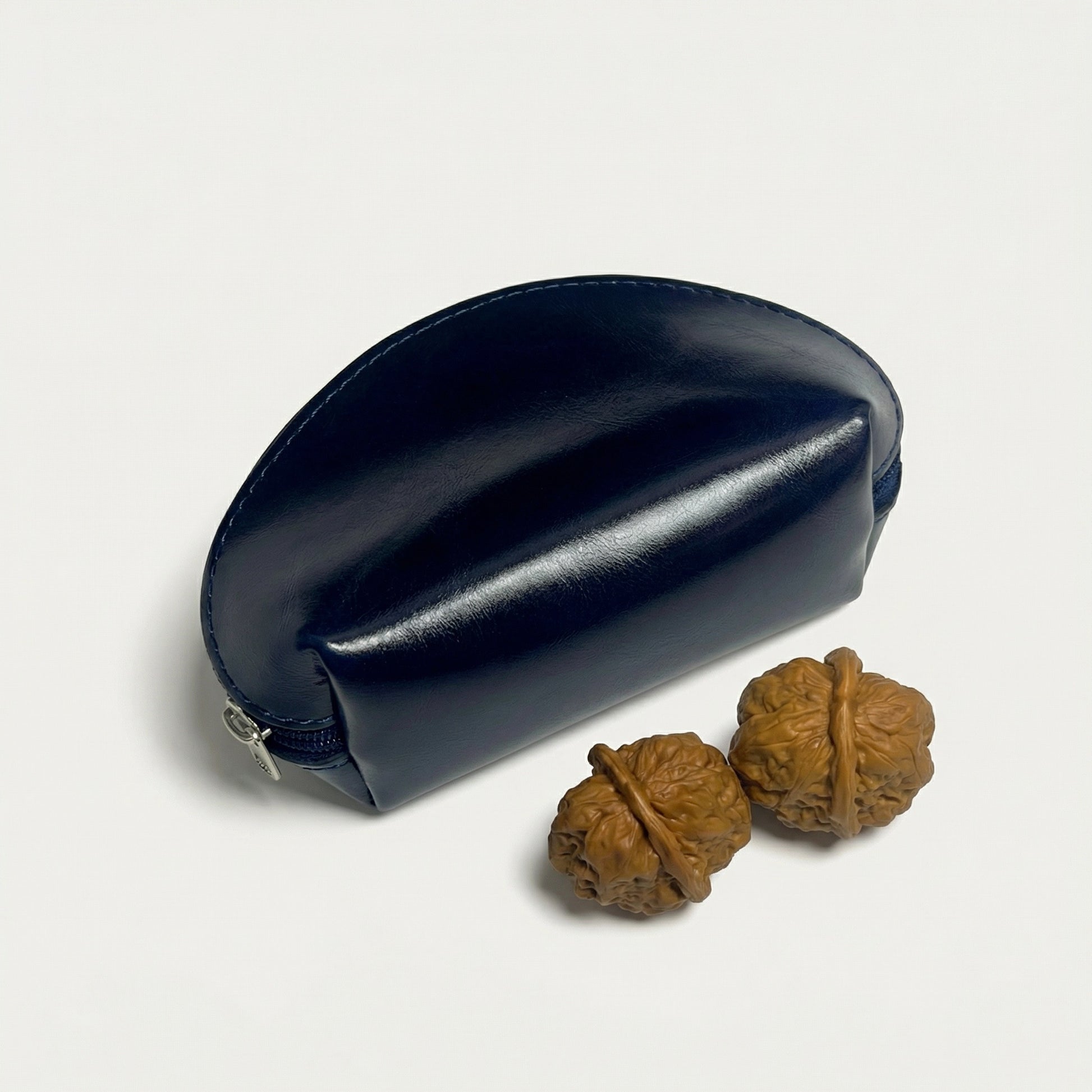 Navy blue leather case with two walnuts on a light gray background