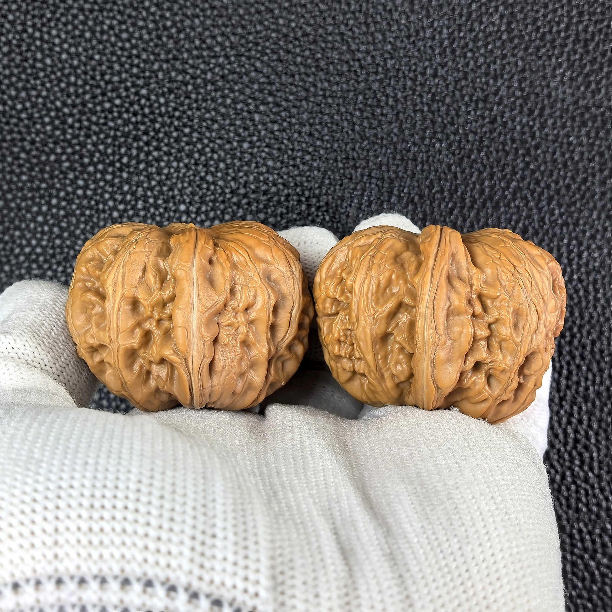 Pair of Pinggu Ingot walnut hand exercisers from ThePatinaProject, 39mm x 42mm, with intricate carved patterns.