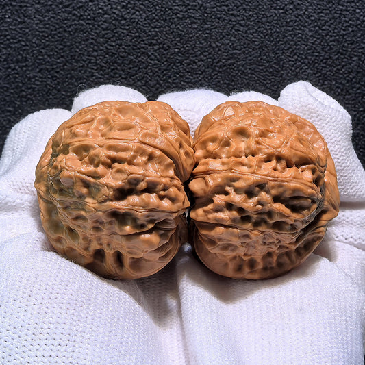 Walnut hand exerciser pair, Pumpkin Squat (Nan Gua Dun) NGD-402, 41mm x 43mm, showing textured walnut surface and ergonomic shape.