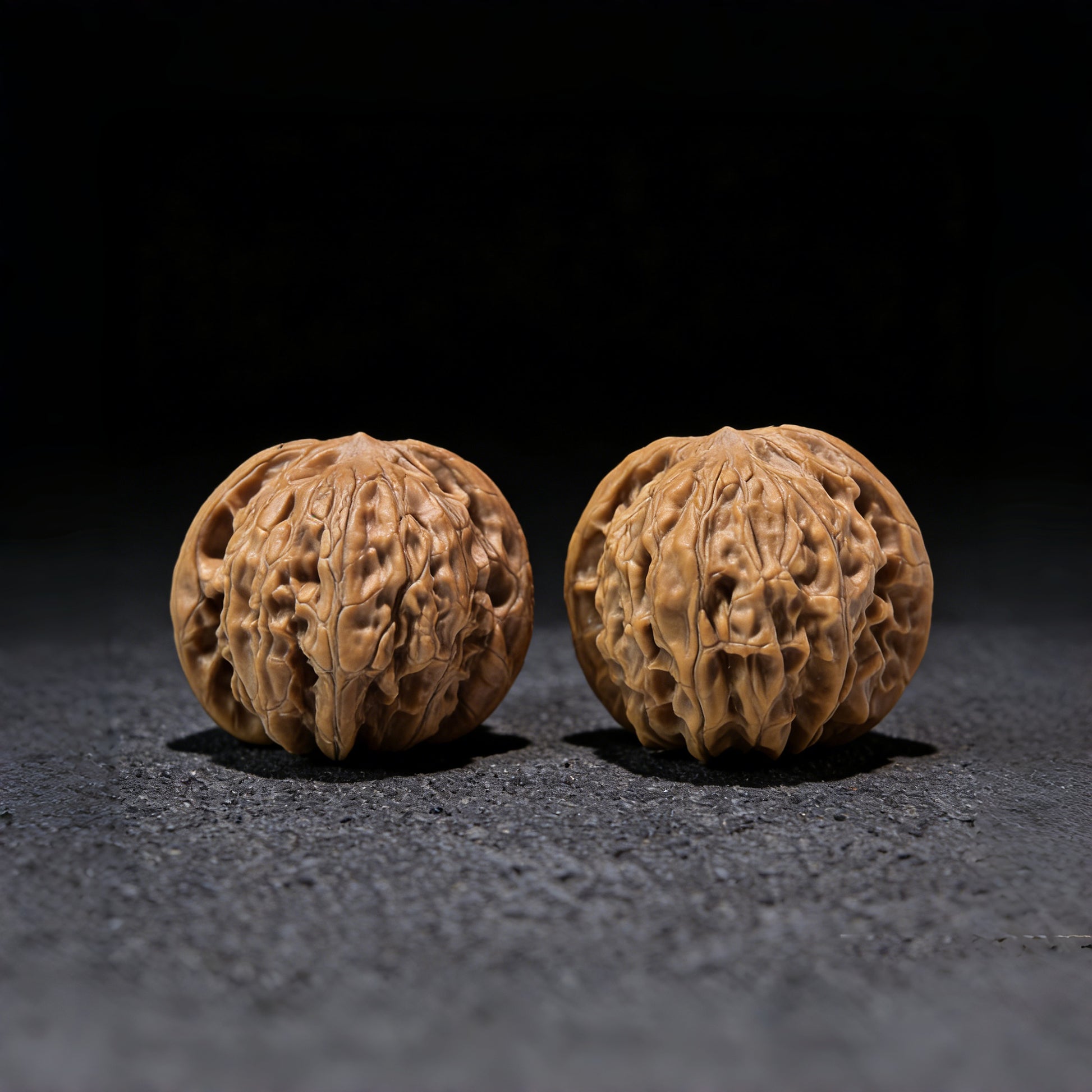 Pair of Small True Millstone walnut hand exercisers by ThePatinaProject, measuring 38mm x 30mm, with textured stone-like surface.